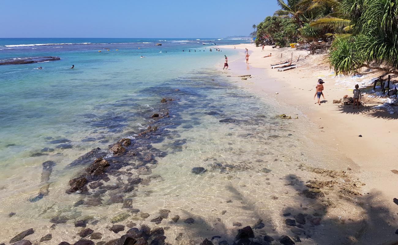 Foto de Madiha Beach con arena brillante y rocas superficie