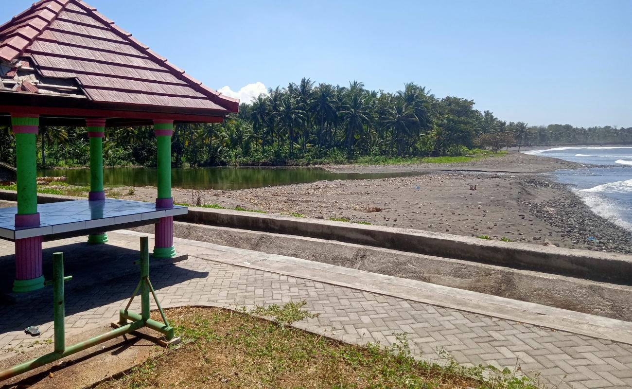 Foto de Dharmawangi Beach con arena/guijarros negro superficie