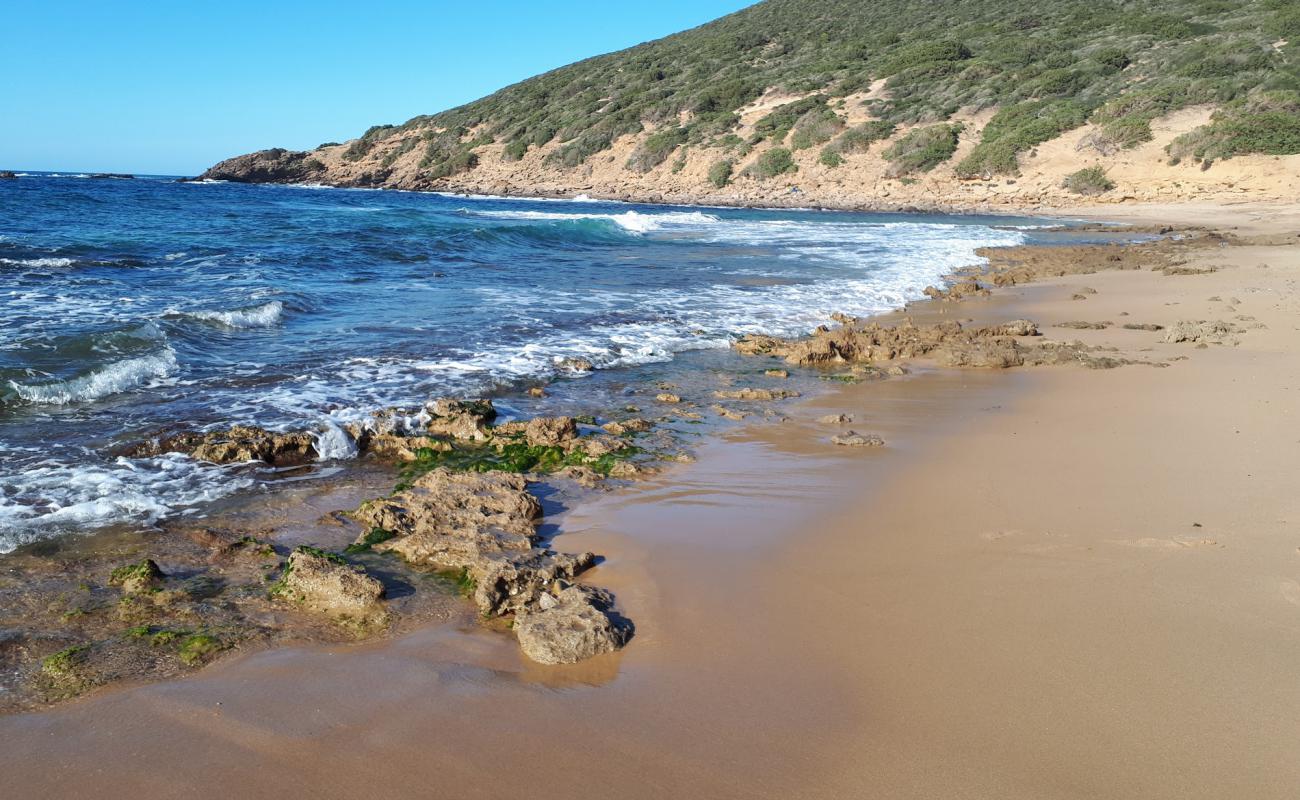 Foto de Portu Sessini con arena brillante y rocas superficie