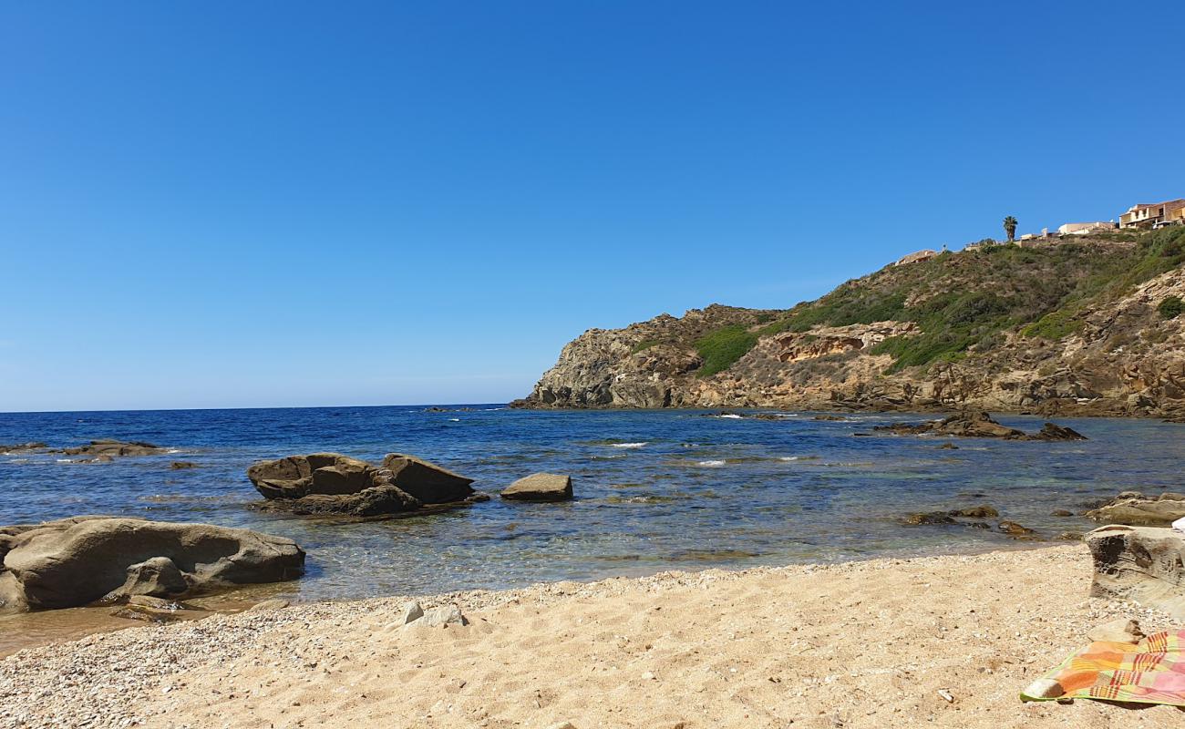 Foto de Cala Is Cannisonis con arena brillante y rocas superficie