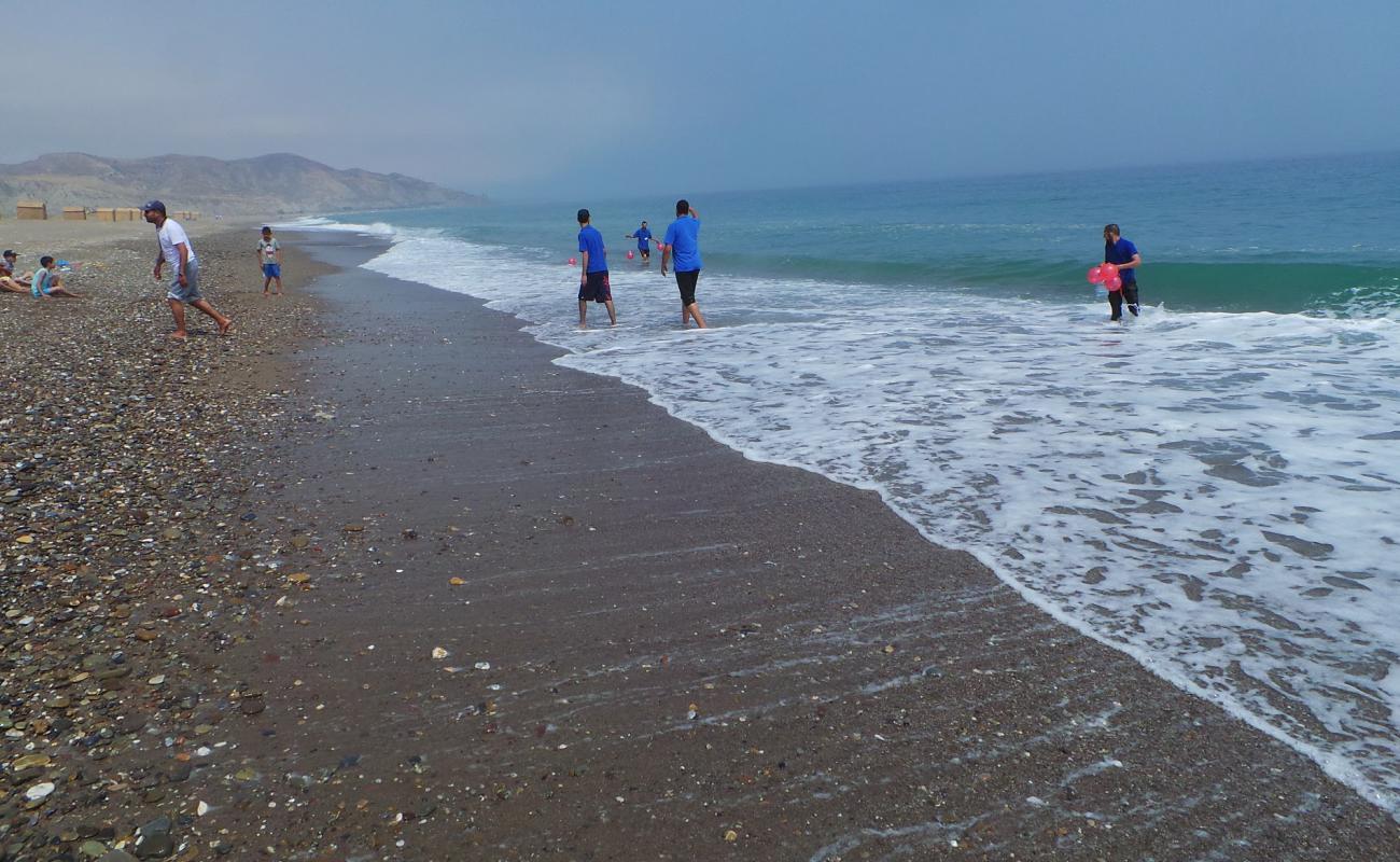 Foto de Plage Sidi Driss con arena gris y guijarros superficie