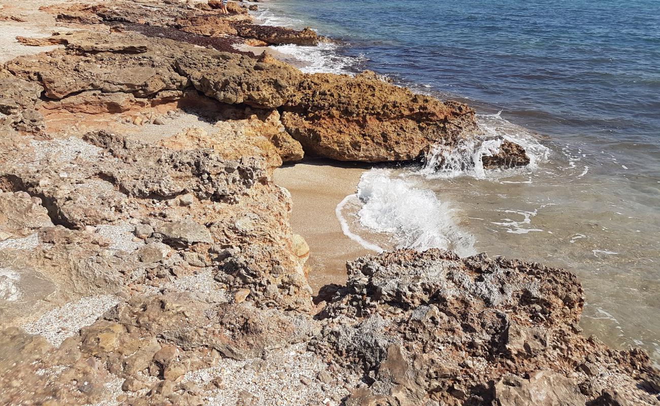 Foto de Cala l'Arjub con arena/piedras marrón superficie