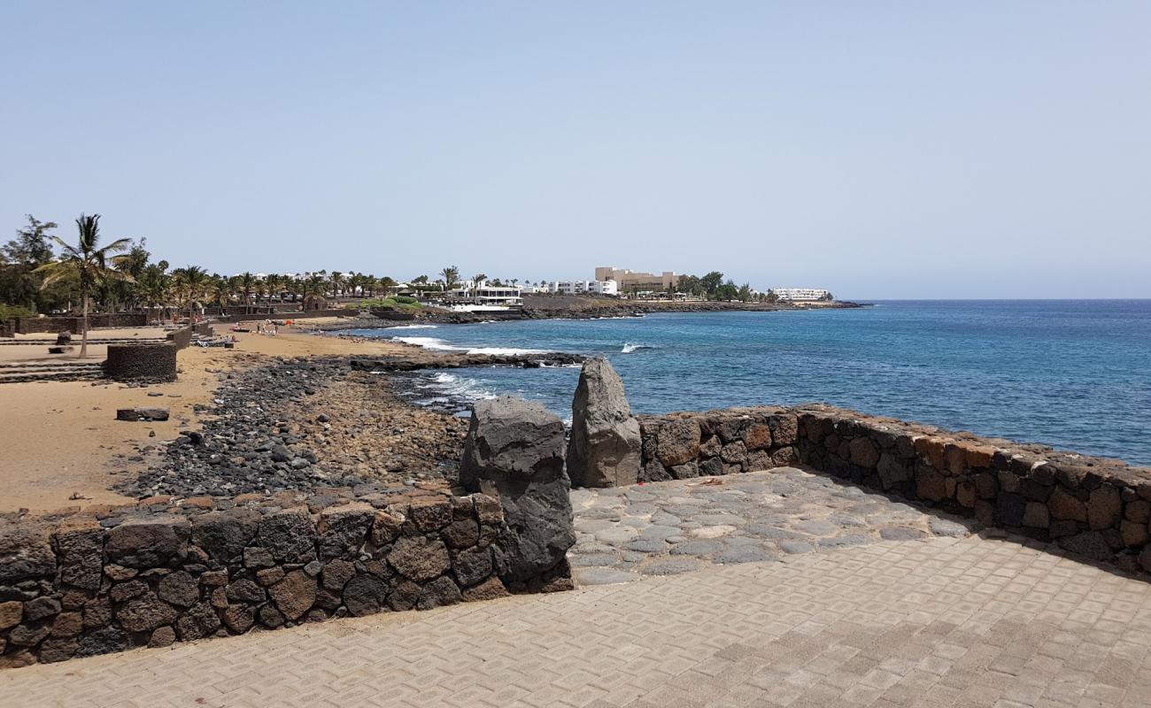 Foto de Playa Bastian con arena/piedras marrón superficie